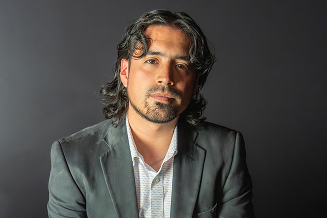 hector jardon wearing a dark suit against a dark background