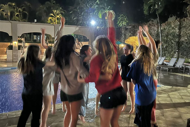 CCU students joyfully gathered in a group in Honduras, with a pool visible in the background