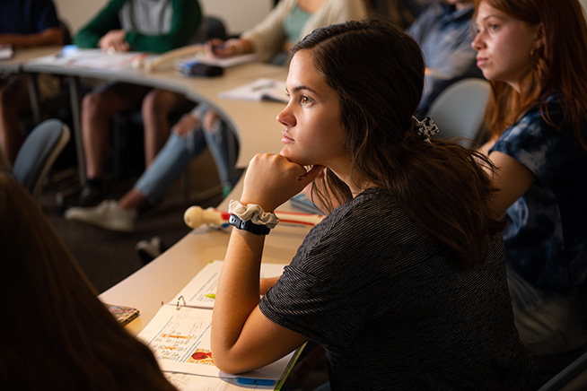 Sierra Rose as a CCU student, sitting at a desk in a classroom with a notebook in front of her