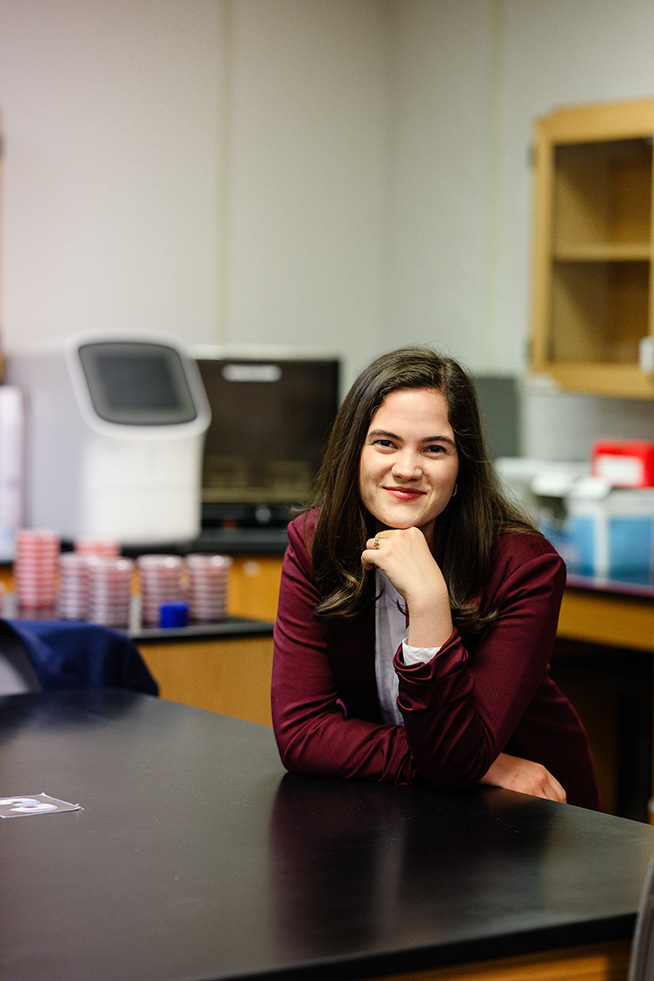 Sierra Rose sitting at a table in a science lab with science equipment in the background